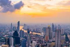 Cityscape with skyscrapers and a river in front of sunset sky